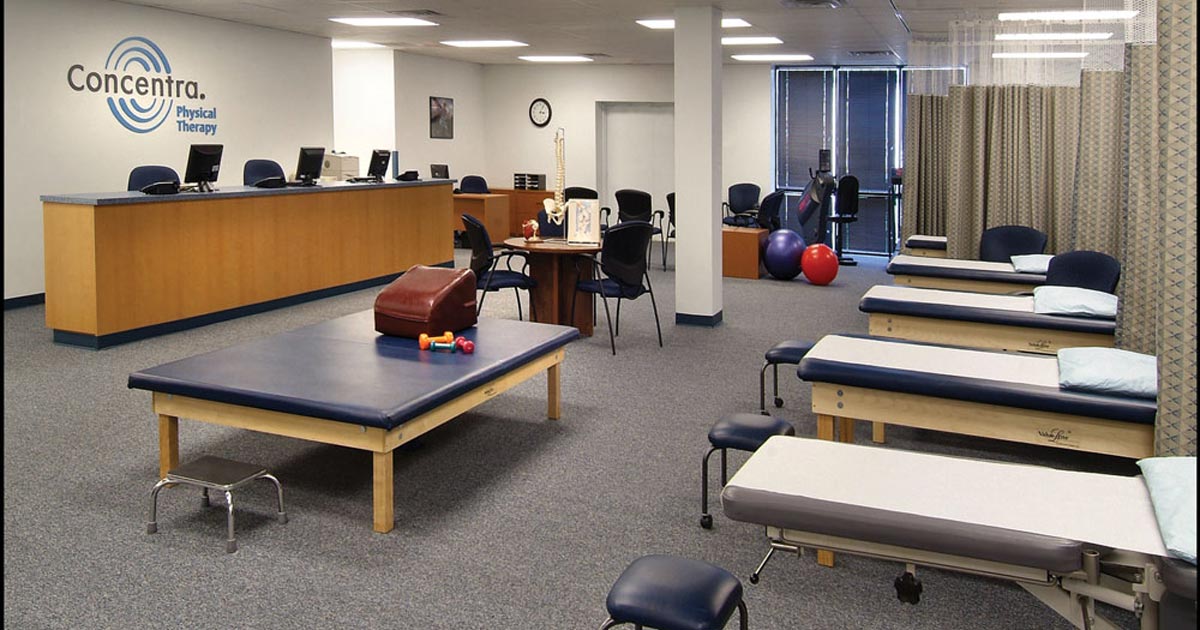 Treatment tables, stools, and rehabilitation equipment inside a Concentra physical therapy facility
