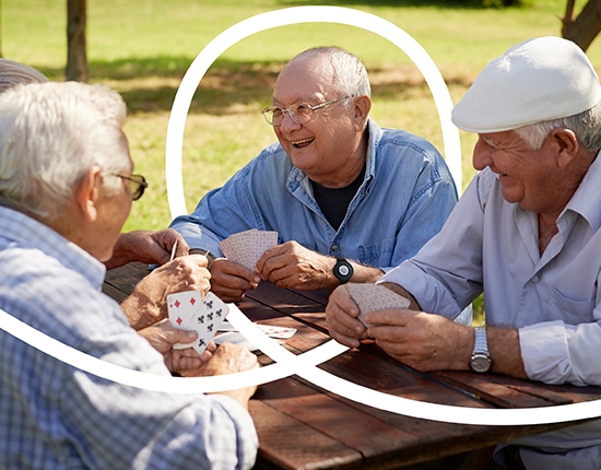 Men playing cards together; one wears a medical alert pendant