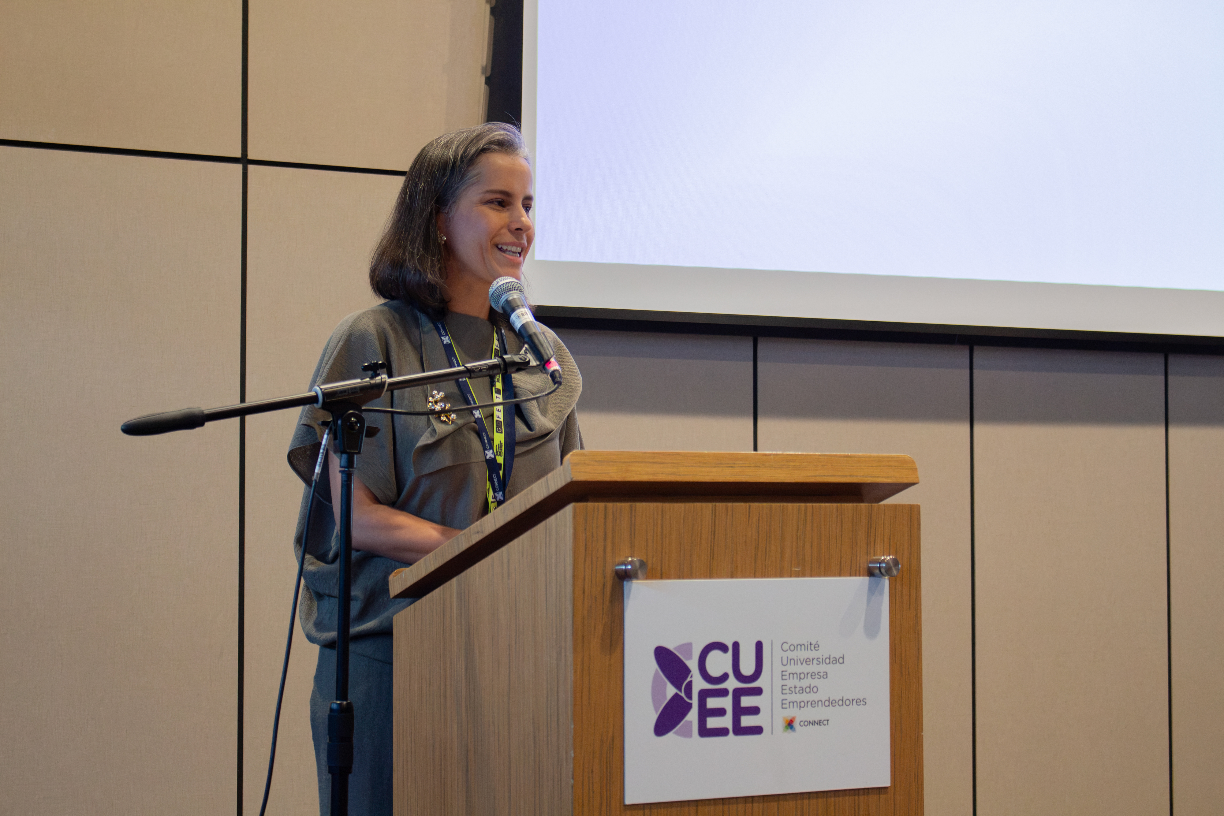 Tatiana León speaking at the CUEEE plenary, with a microphone and lectern