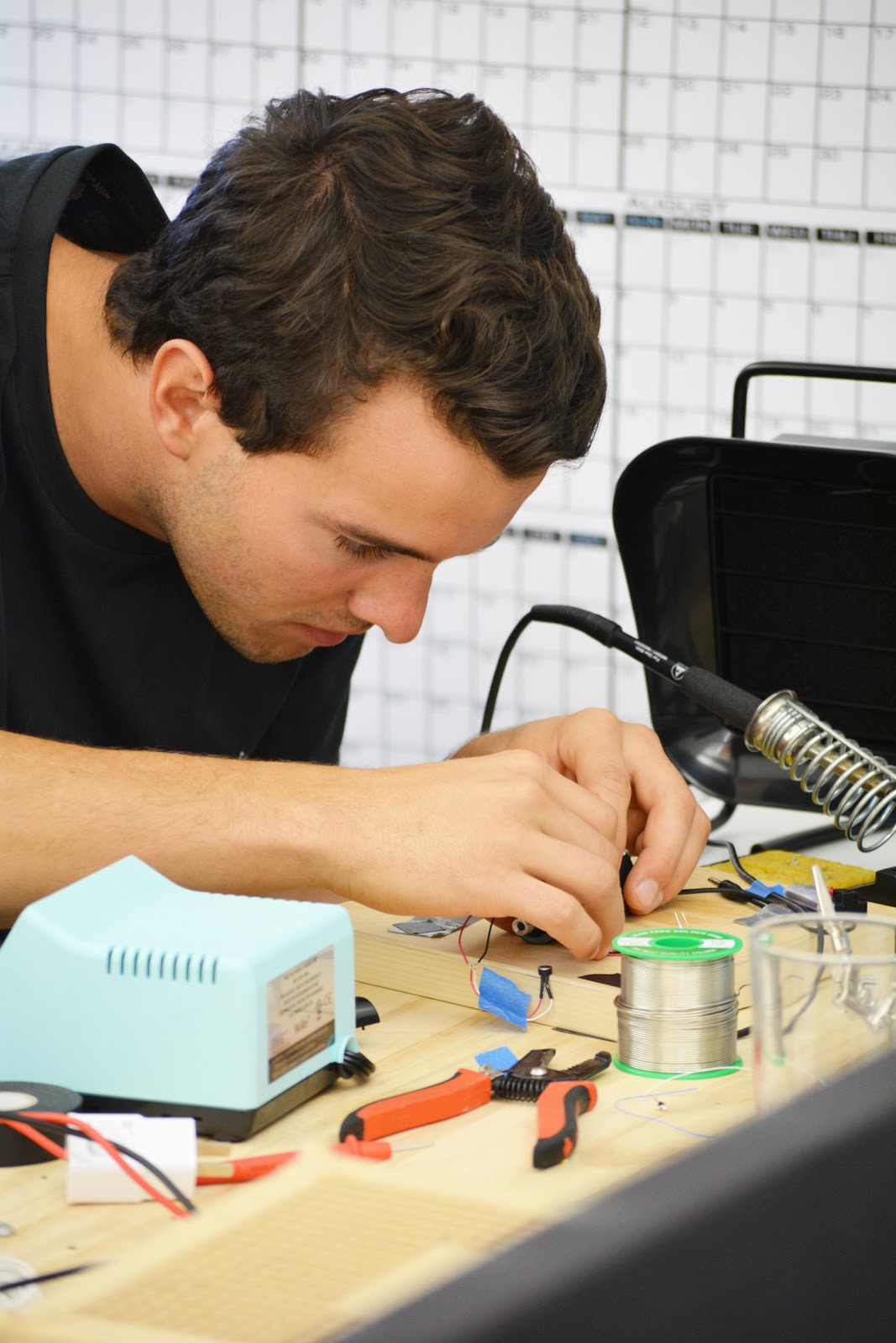Connor Landgraf leaning over a workbench, soldering electronic components
