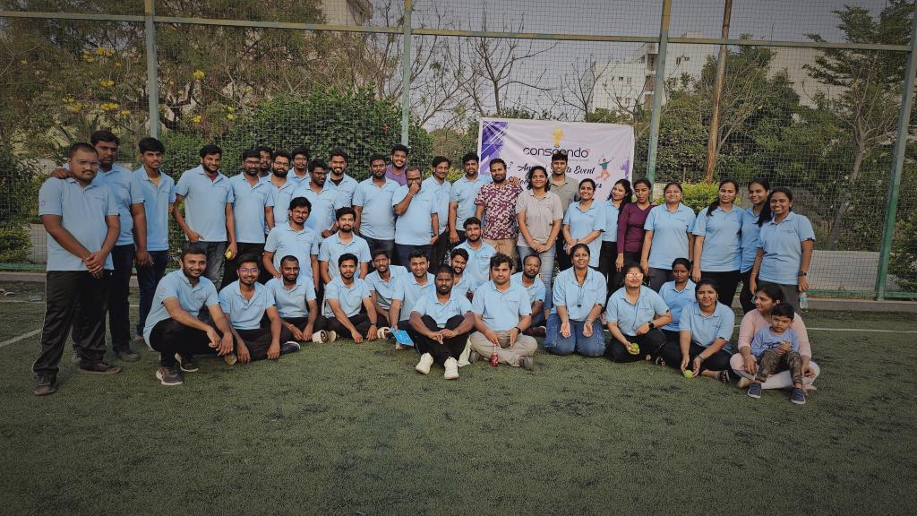 Conscendo colleagues in blue polo shirts gathered on a sports field at the company's annual sports event.