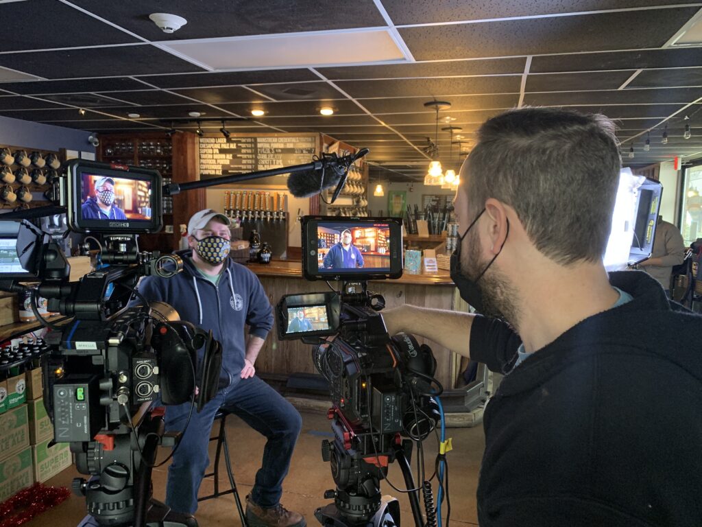 A Consociate Media production crew films an interview at a brewery