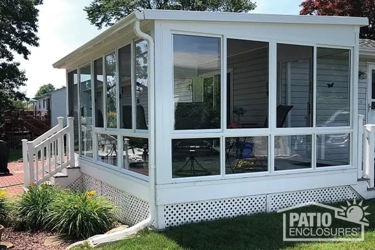A glass-walled Patio Enclosures sunroom beside a landscaped garden