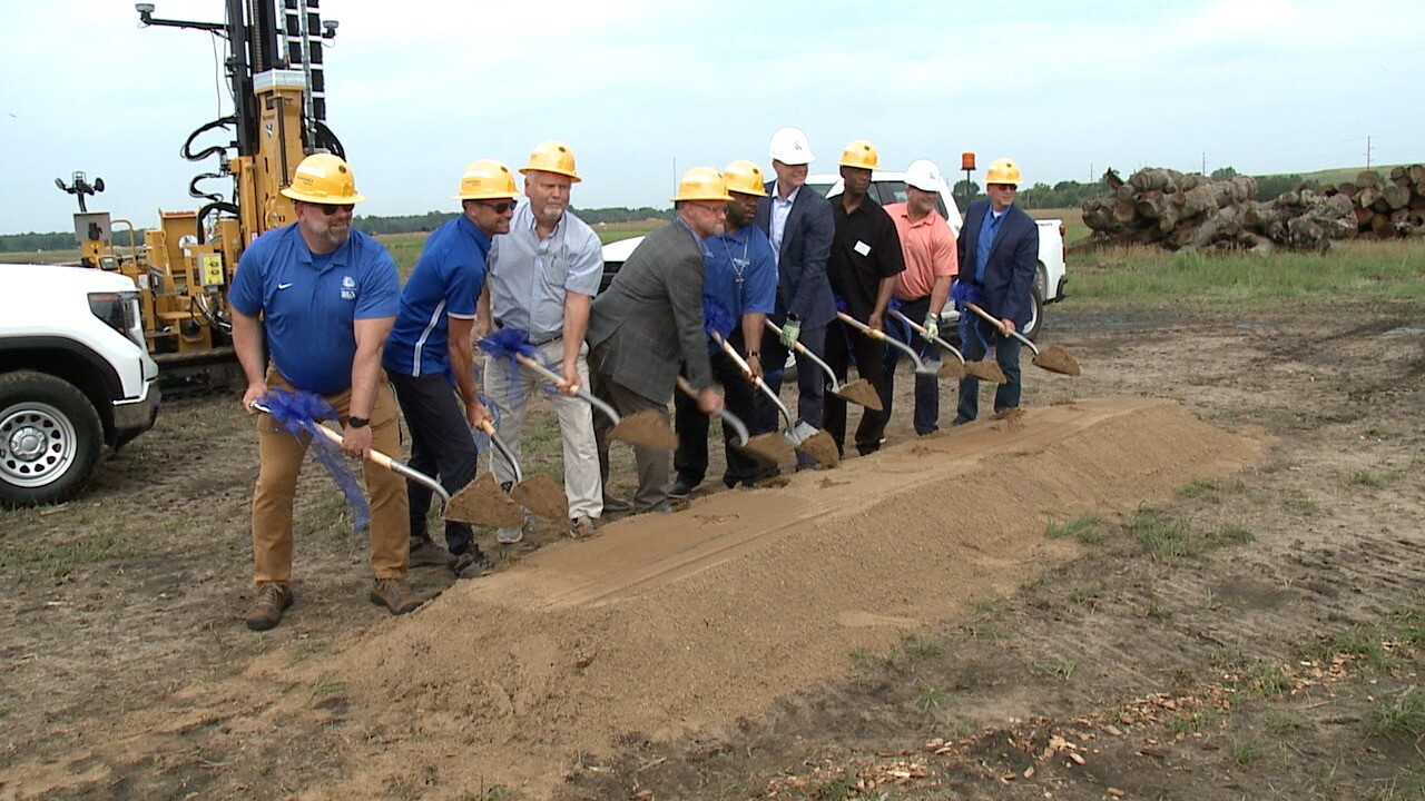 Hard-hatted participants lift ceremonial shovels at the Muskegon solar project groundbreaking