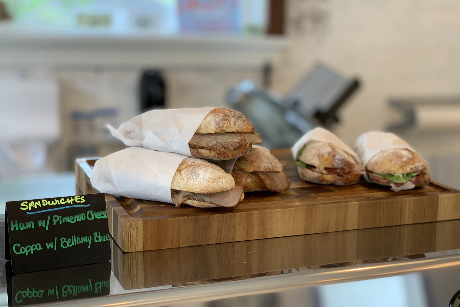 Wrapped artisan sandwiches displayed on a wooden counter
