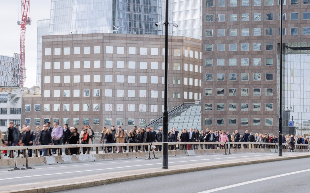 Commuters crossing a London bridge beside office buildings