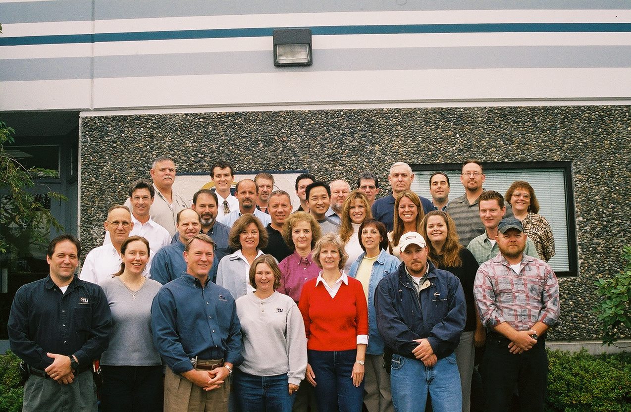 The Telecom Labs team gathered outside a building in an archival company photograph