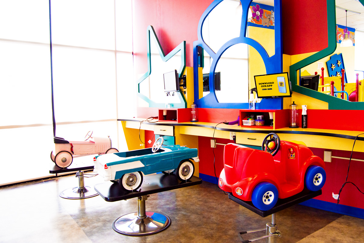 Colorful Cookie Cutters salon with red and blue vehicle-shaped haircut chairs