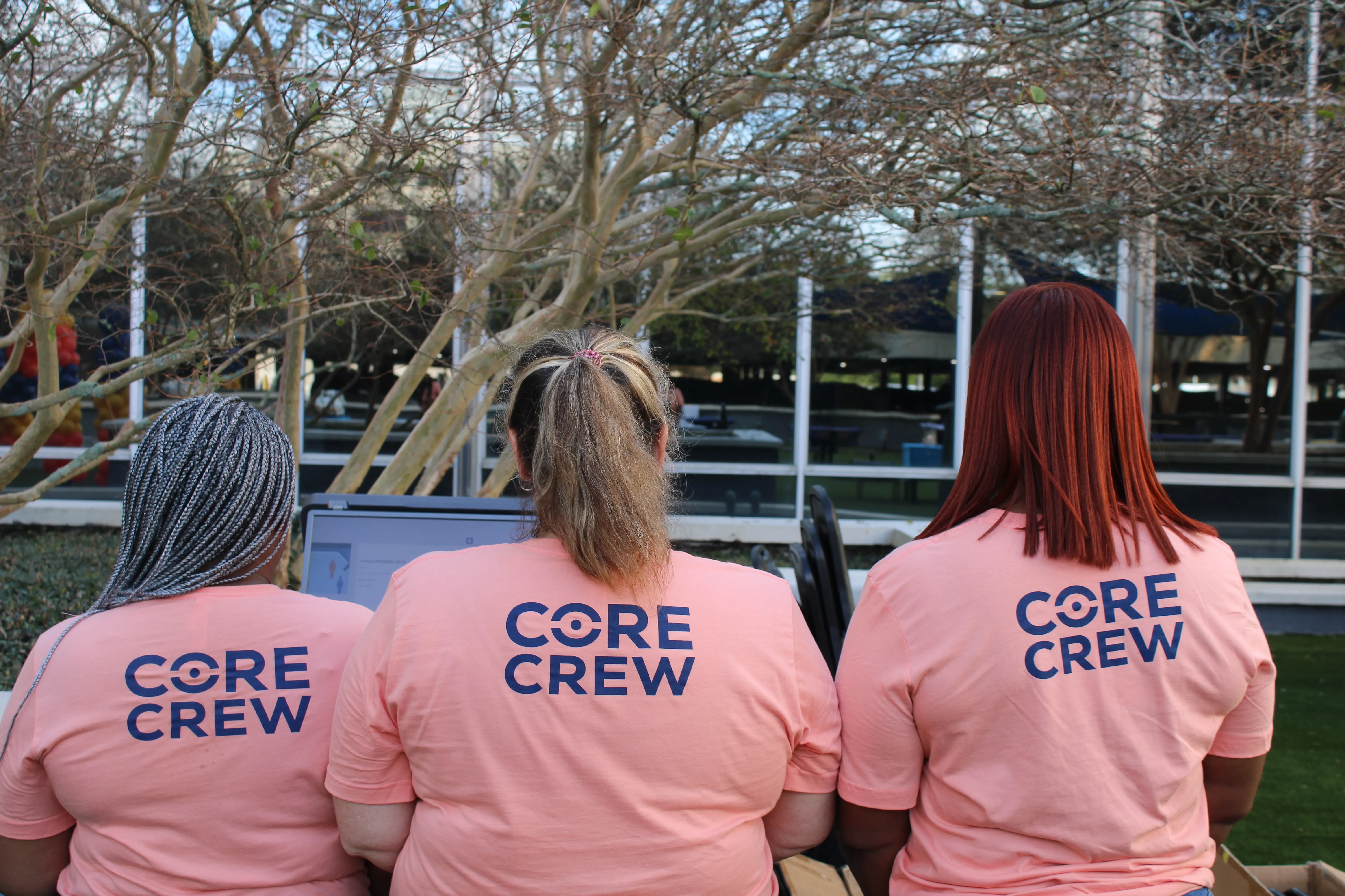 Three Coreforce team members wearing matching pink Core Crew shirts.