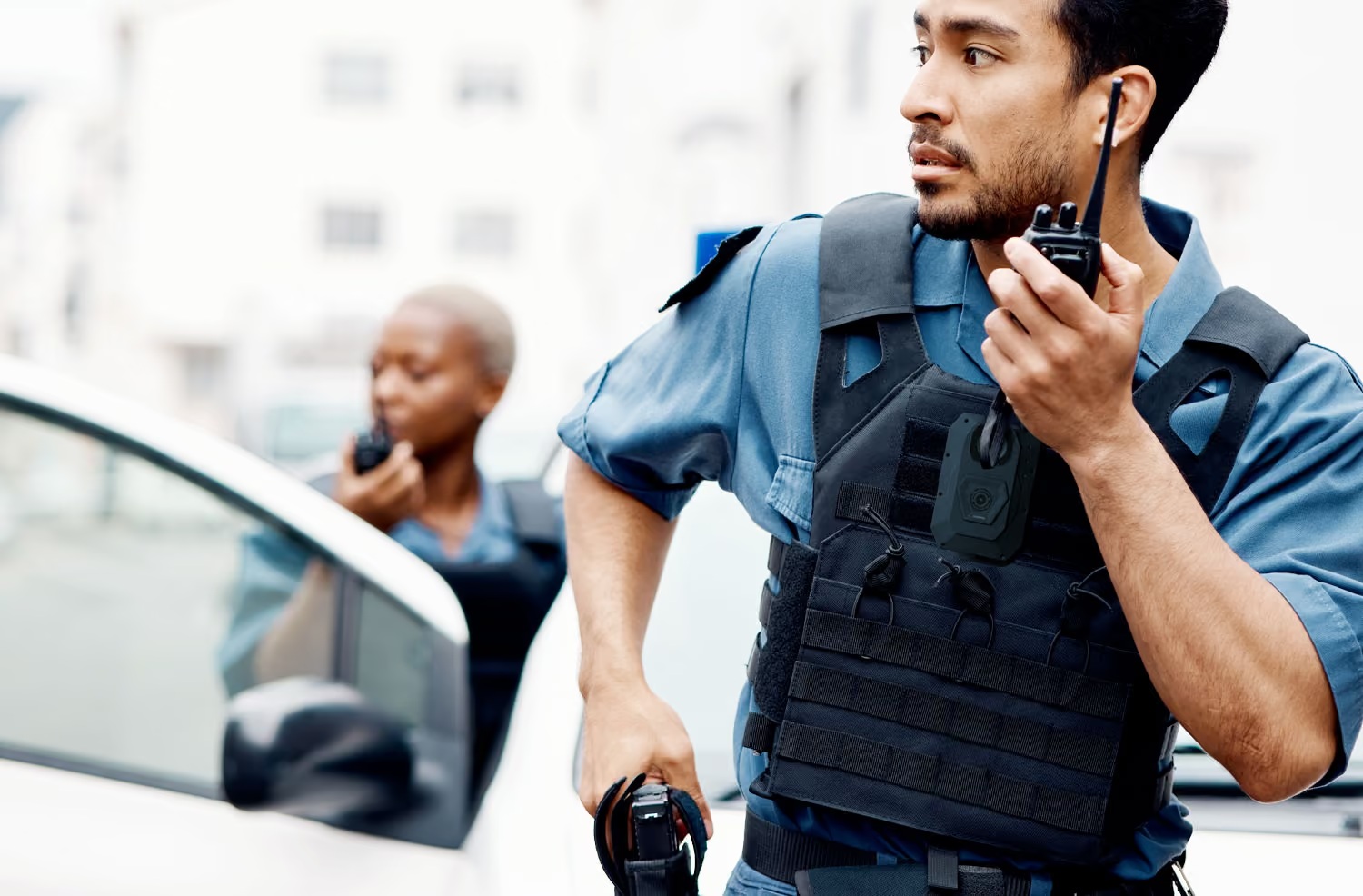 Coreforce promotional photograph of two uniformed officers beside a patrol vehicle, with a body camera visible.