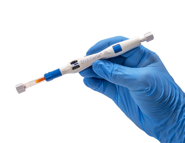 A blue-gloved hand holding CorneaGen’s white EndoSerter-PL graft insertion device
