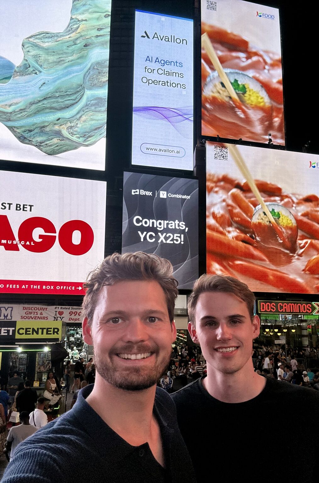 Cornelius Schramm and Bryan Guin smiling beneath an Avallon display in Times Square