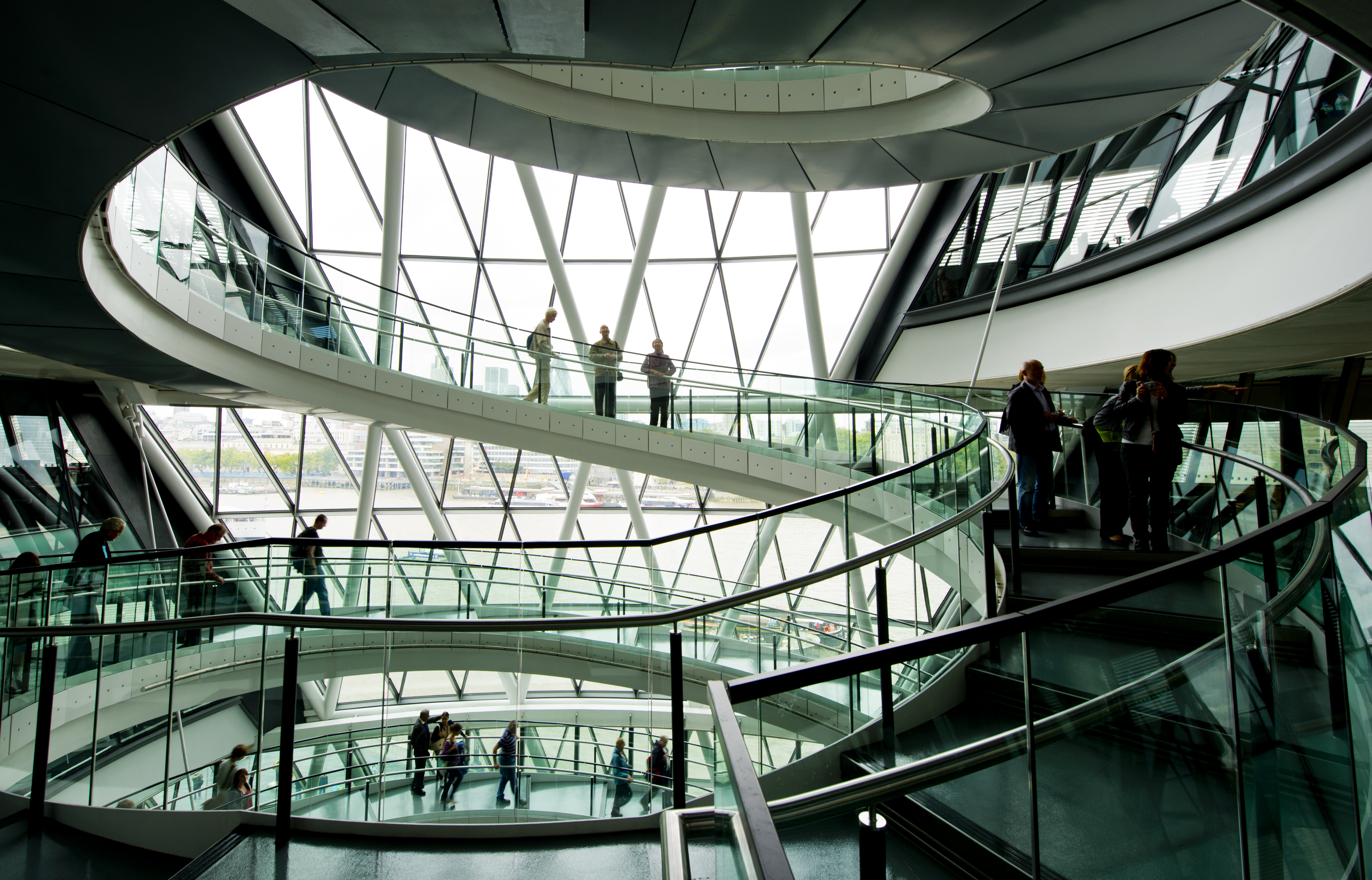 People moving through the curved walkways of a modern glass building