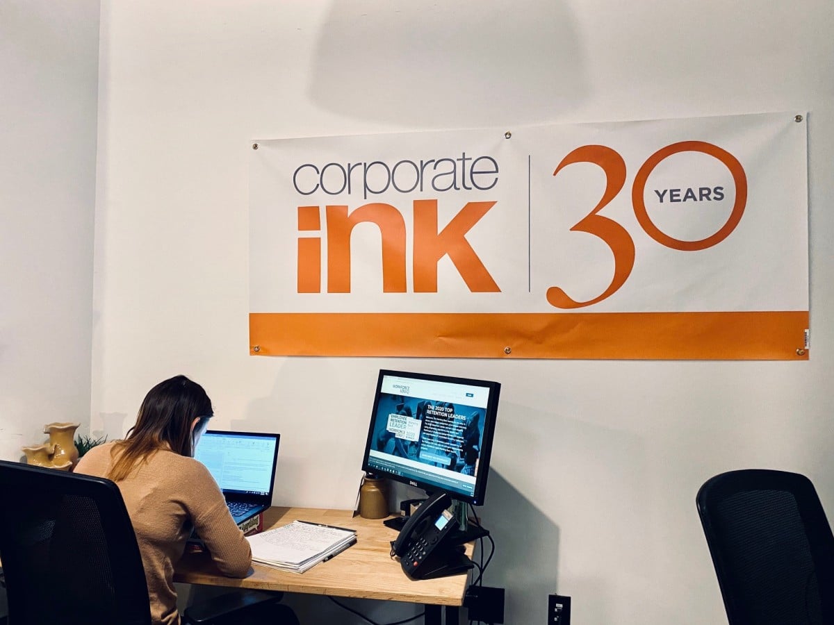 Corporate Ink's 30th anniversary banner above a workstation in its office