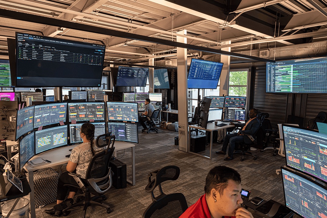 Corva operations center staff monitoring wellsite information across multiple screens