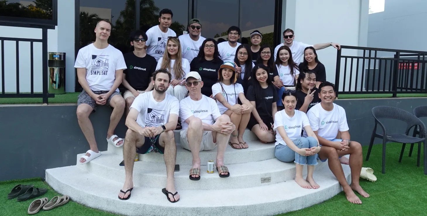 The Simplesat team gathered together on outdoor steps, wearing company T-shirts.