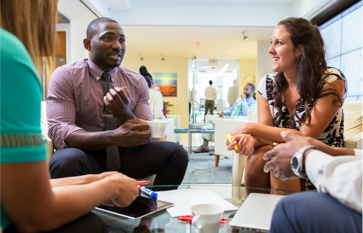 CoStar colleagues discussing work around a table in an official careers photograph