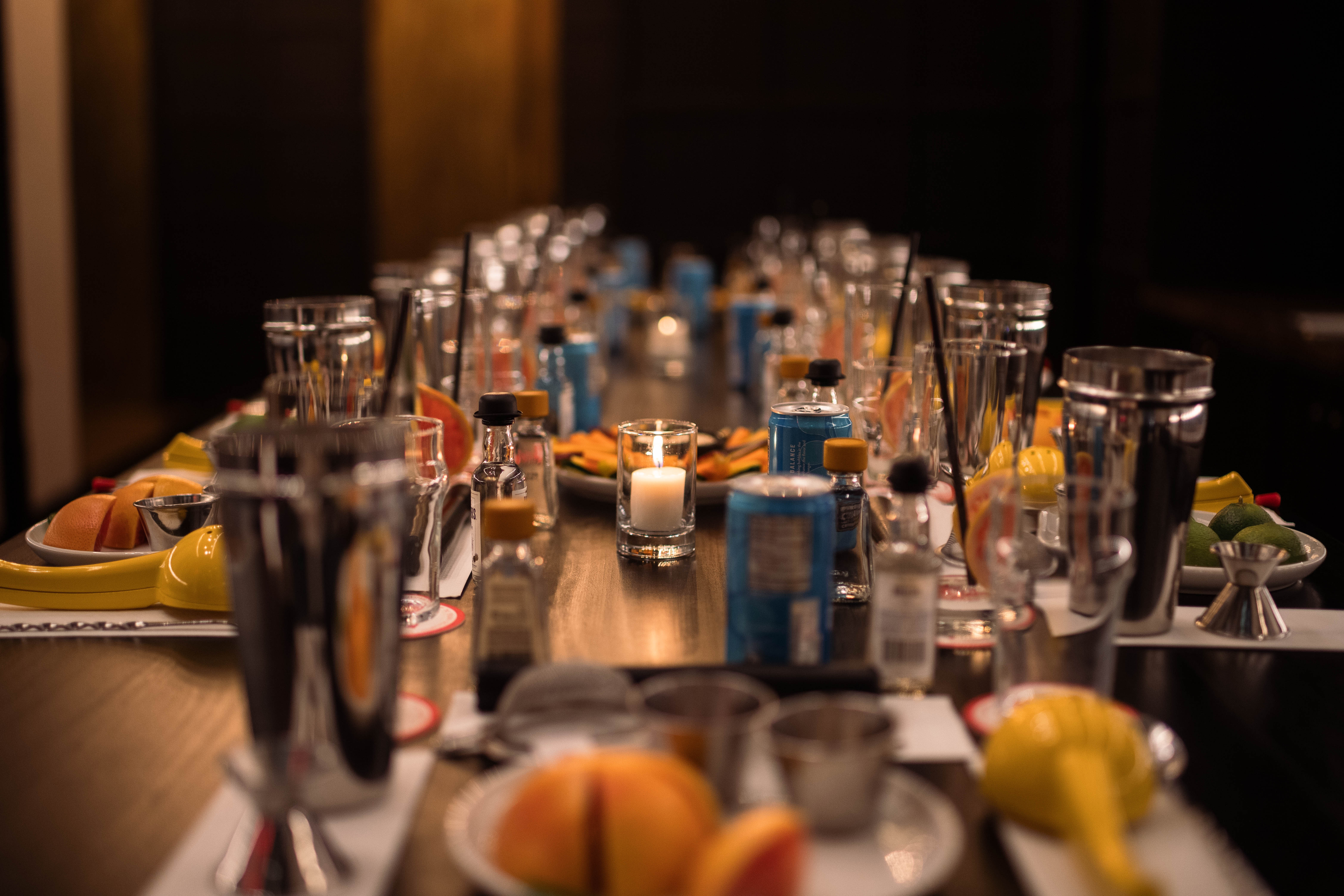 Cocktail-making stations arranged along a table with shakers, citrus and measuring tools