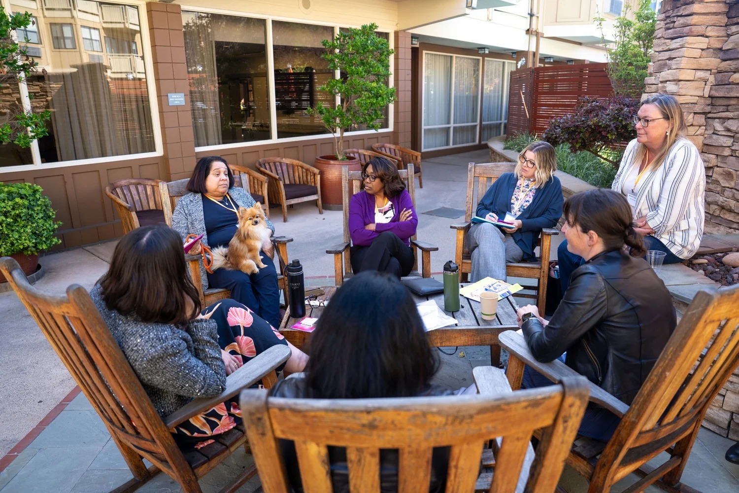 Summit participants discussing healthcare in an outdoor circle, with a small dog among them