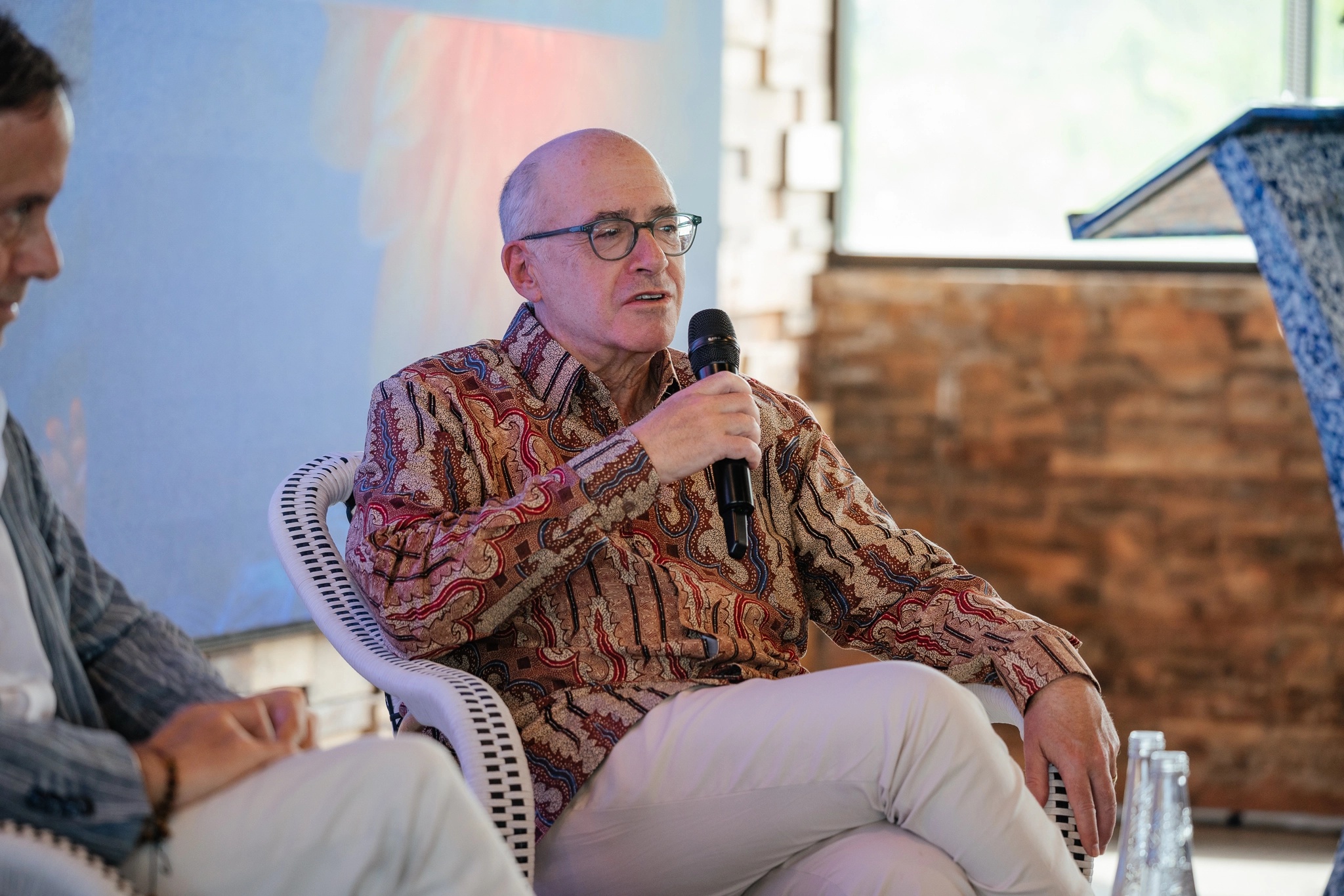 Craig Cogut wearing a patterned shirt and speaking into a microphone at a Bali dialogue