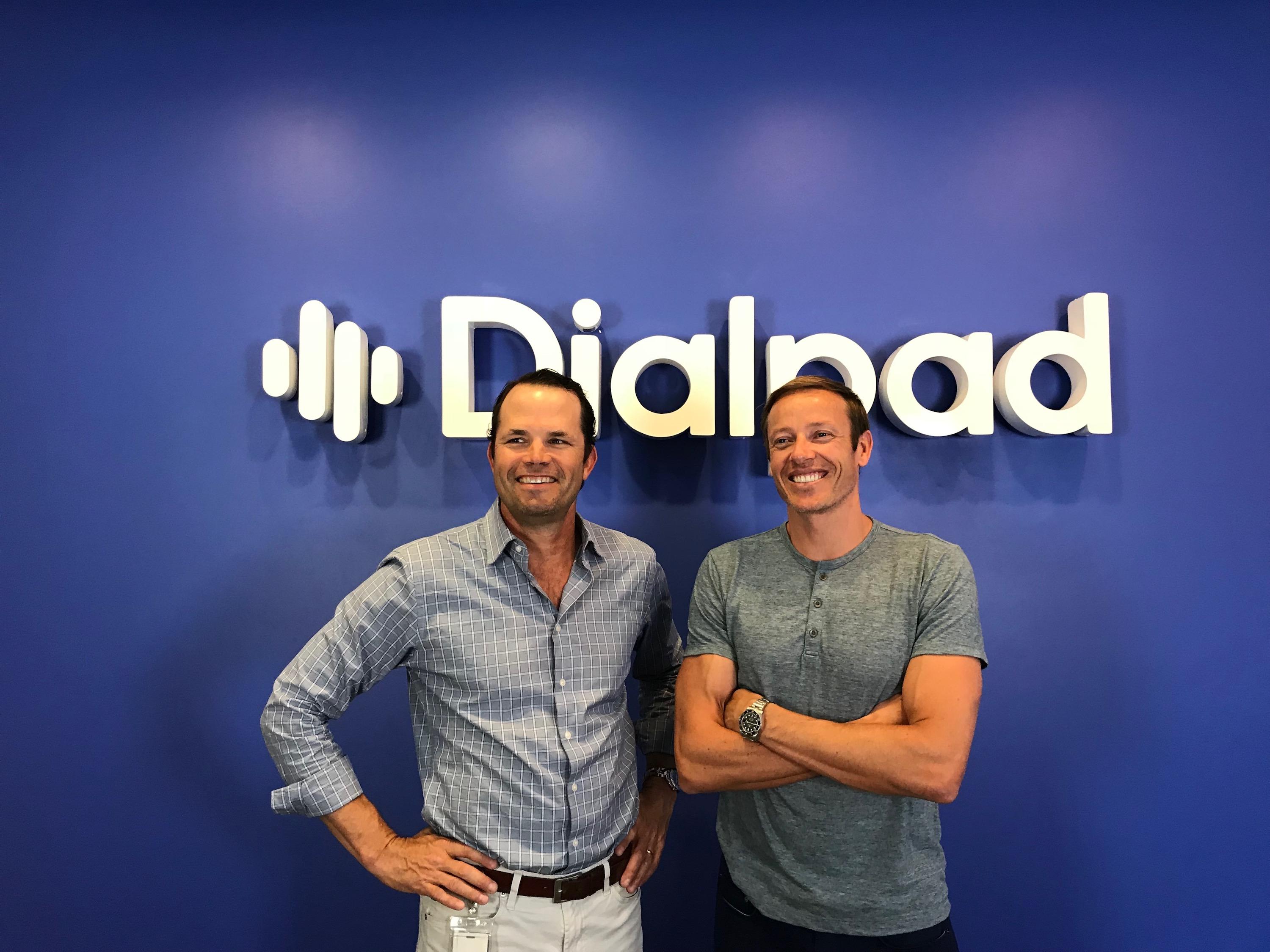 Craig Walker, left, and Dan O’Connell smiling in front of a Dialpad sign