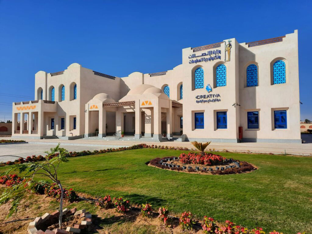 CREATIVA Aswan building with blue windows, pale walls and landscaped grounds
