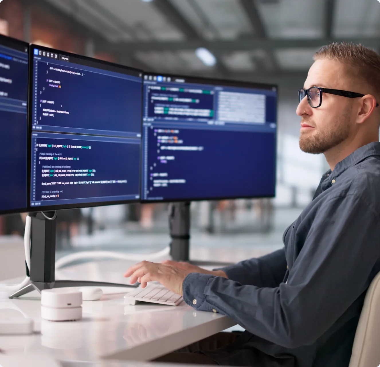 Developer at multiple monitors in illustrative imagery published by Creative Chaos