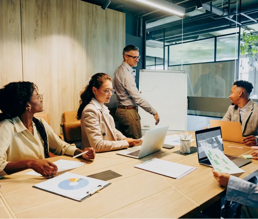 People discussing work around a table in an illustrative image from the company website