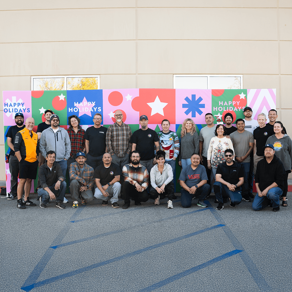 CGS team and family gathered in front of a colorful holiday backdrop