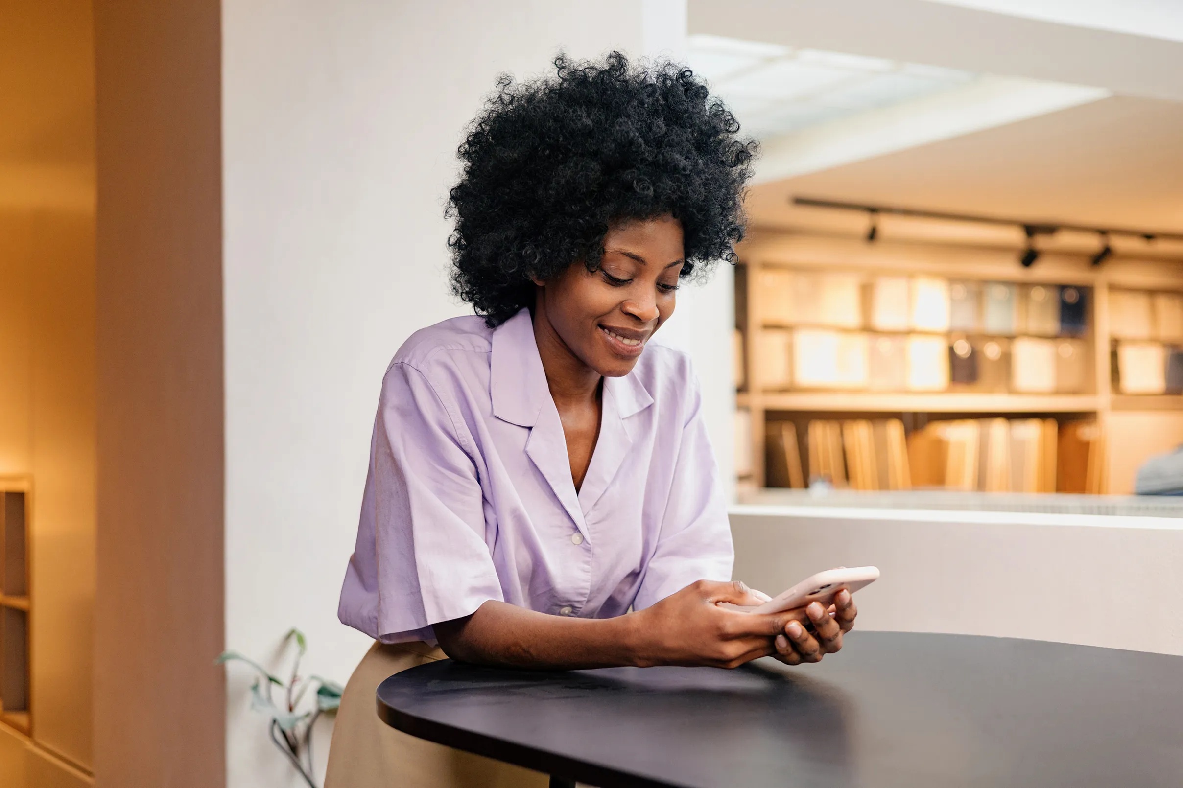 A woman looking at her smartphone at a cafe table, from Credit Genie's company website