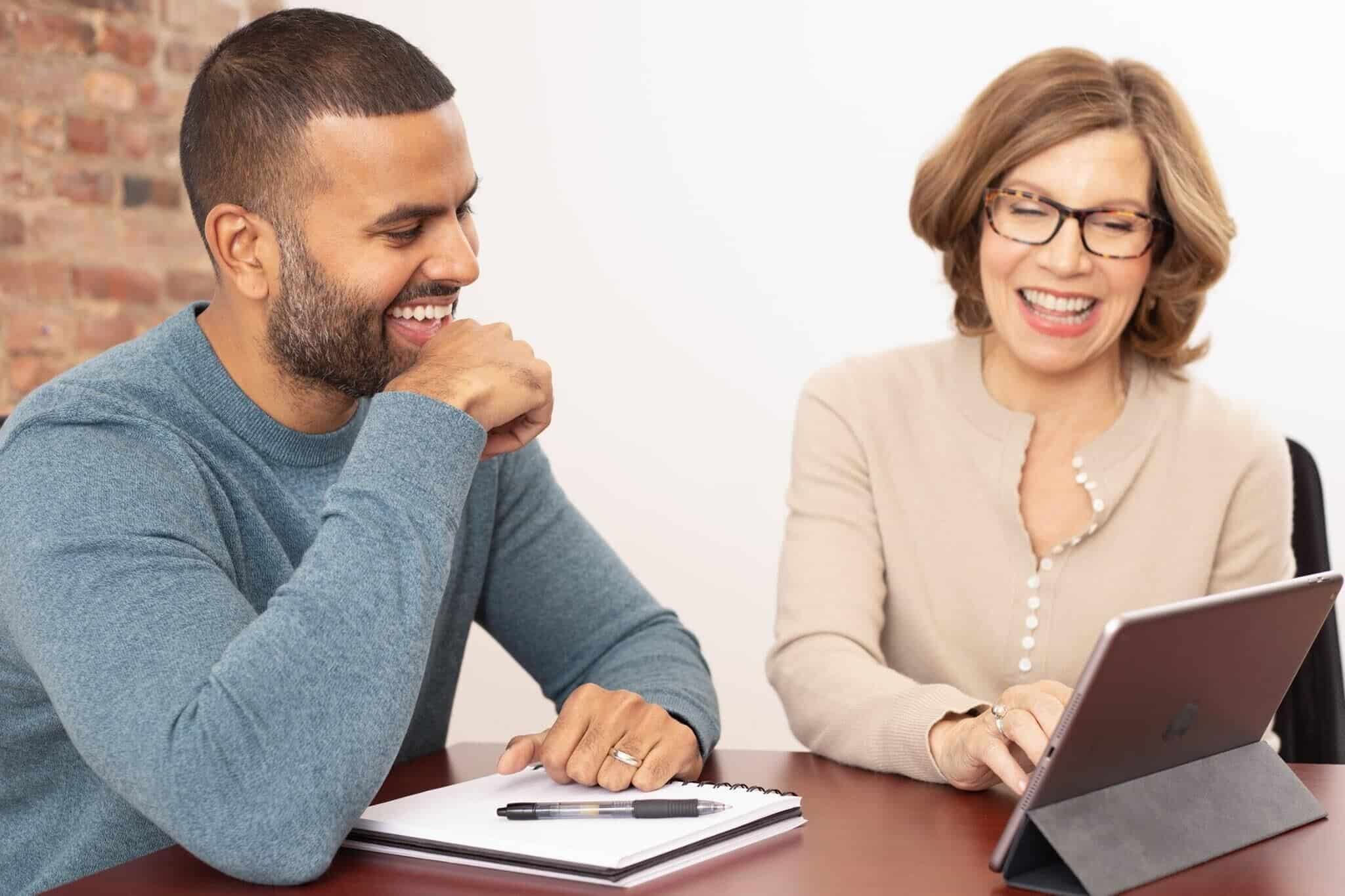 Two Crenshaw Communications colleagues smiling during a working session at a table