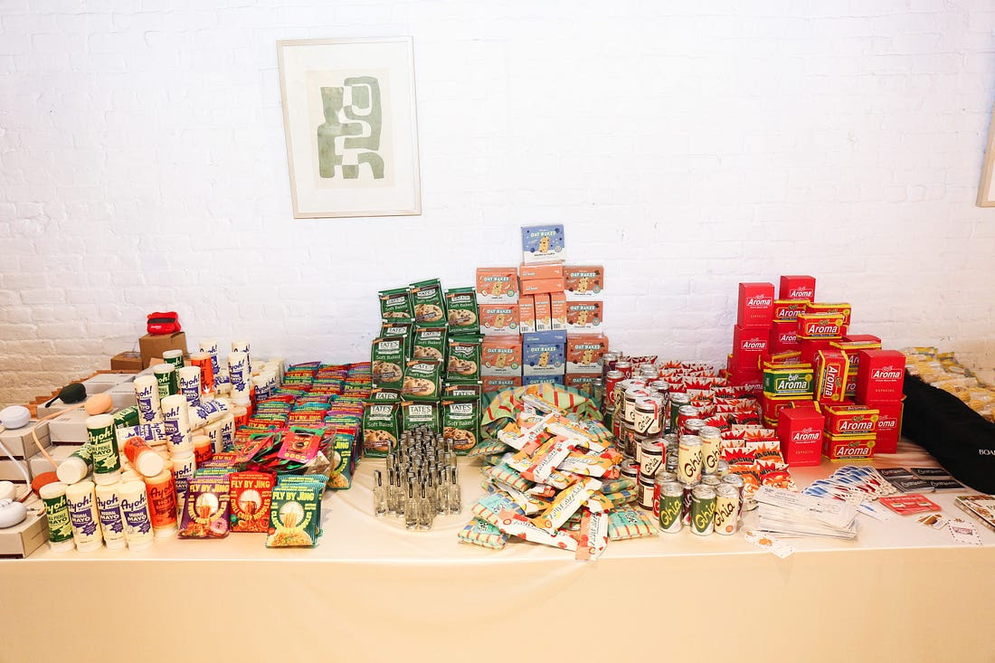 A table of packaged food and drinks, including Ayoh, Fly By Jing, Tate’s Bake Shop, and Ghia, pictured in Cristina’s Coolstuff NYC interview.