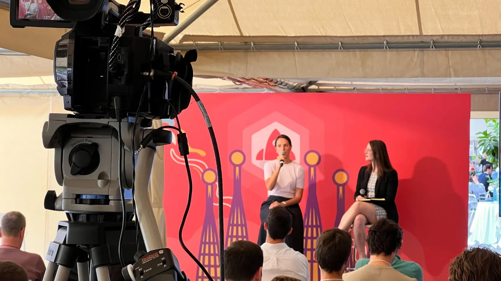 Cristina Vila speaking into a microphone at SaaStr Europa in Barcelona, with a camera and audience in the foreground