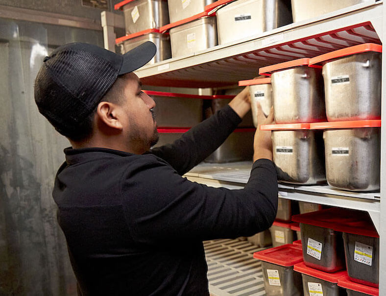A Chipotle employee checking inventory in a restaurant walk-in
