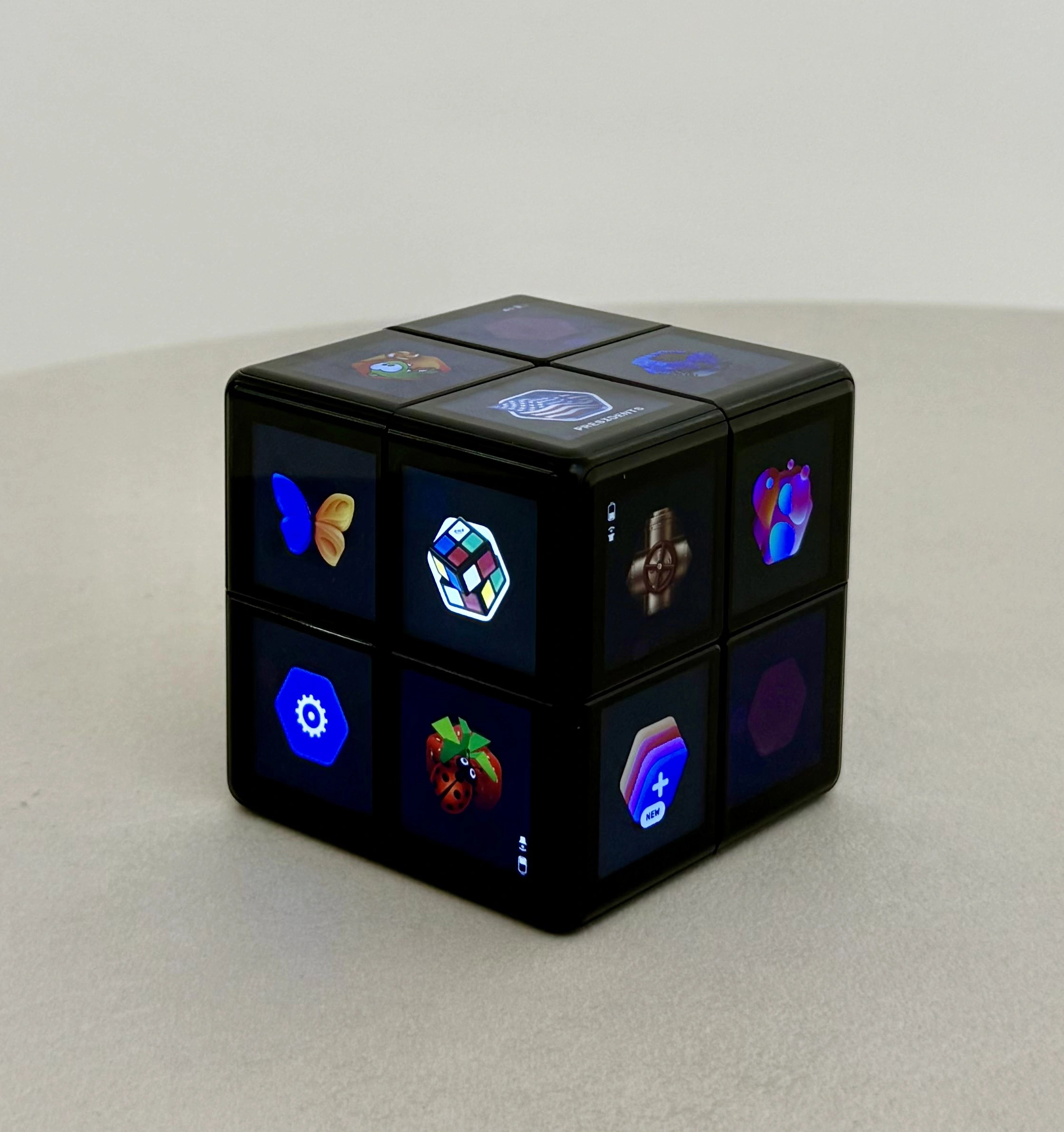 The WOWCube handheld gaming cube showing colorful screens across its faces