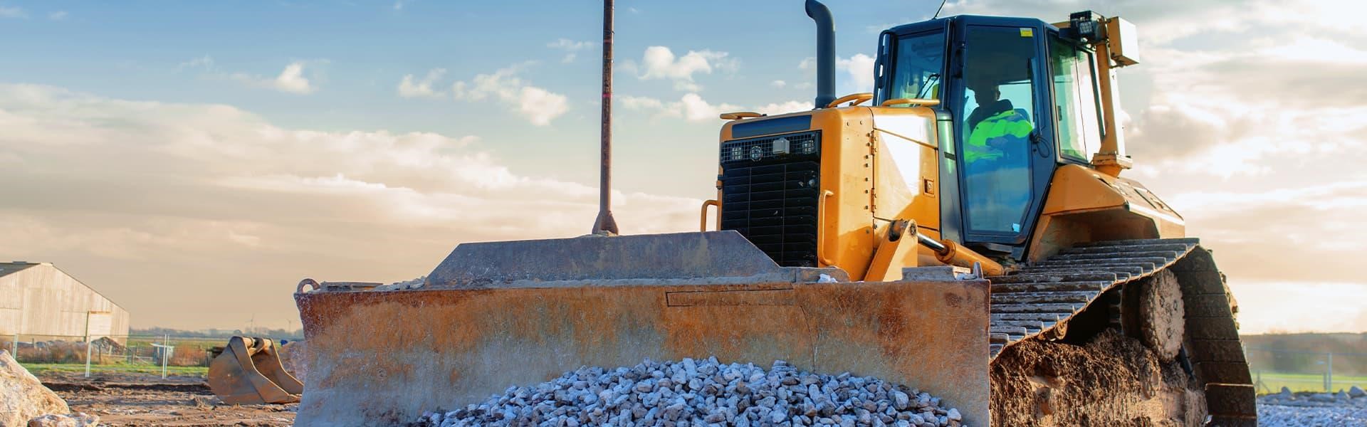A yellow tracked bulldozer moving aggregate at a work site