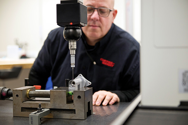 A Curtiss-Wright employee inspecting an aerospace sensor component
