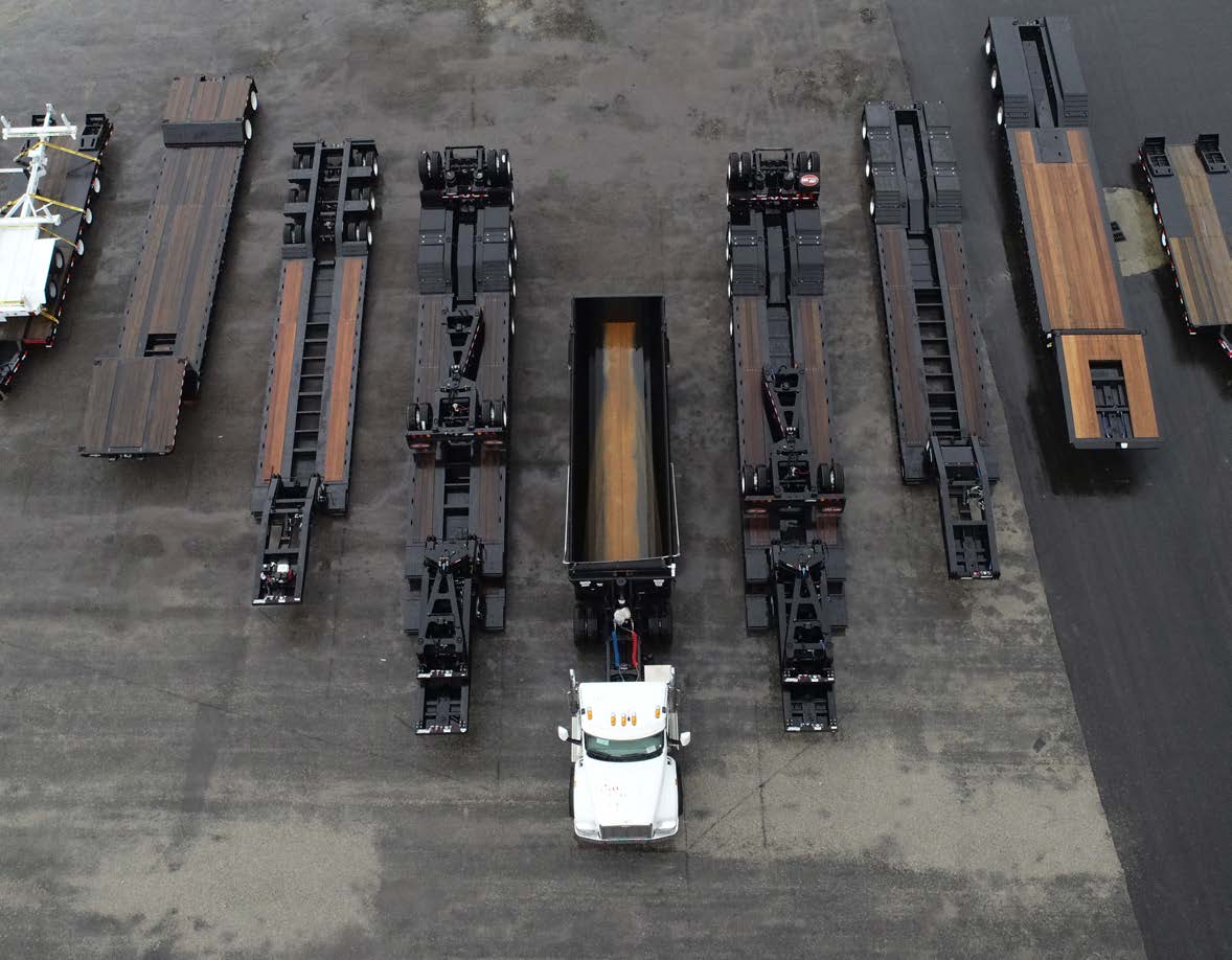 An overhead view of specialty trailers and a white truck arranged in an equipment yard