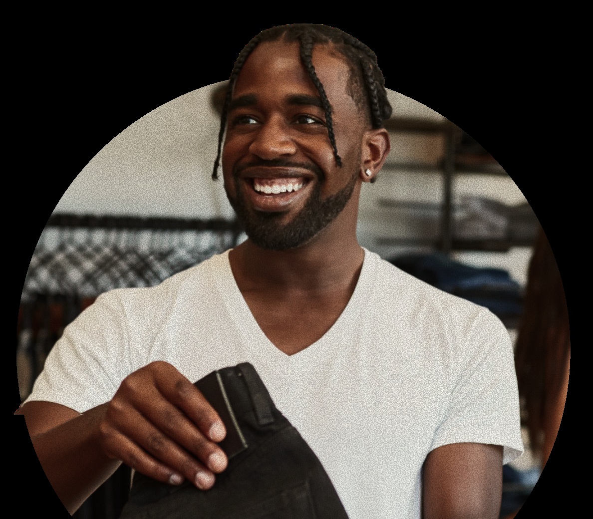 A smiling person holds a pair of trousers in a clothing store in DailyPay’s marketing photograph.