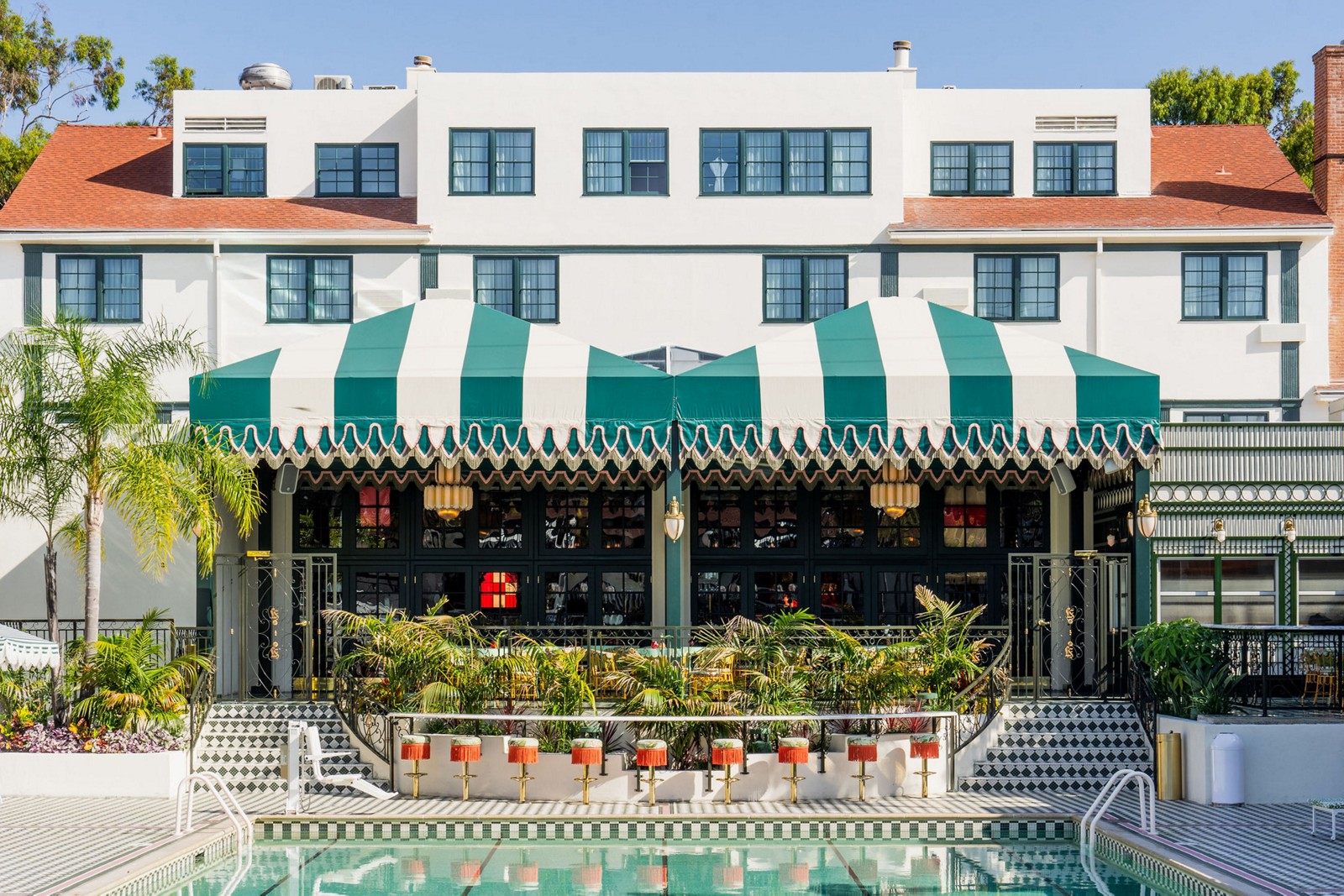 Lafayette Hotel poolside bar with green and beige mosaic tile, striped shades and orange stools