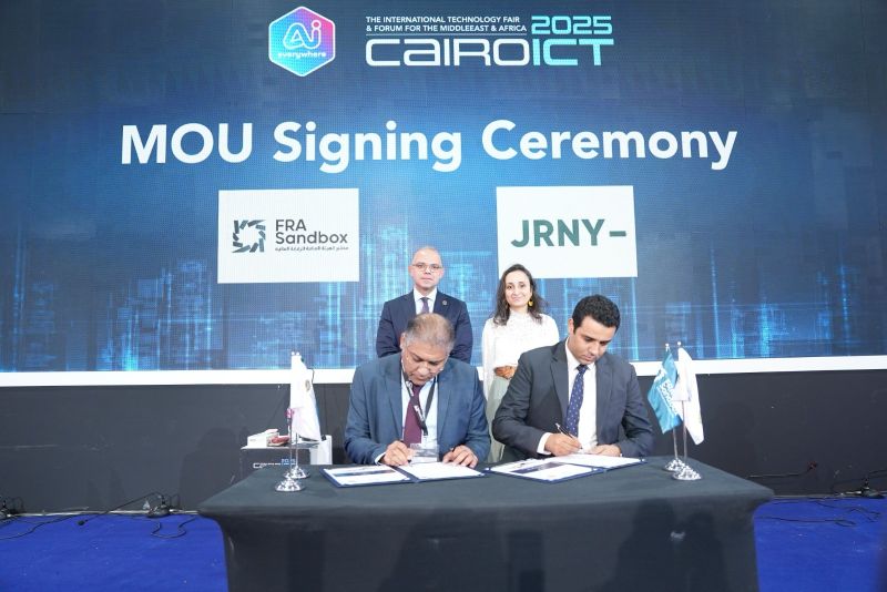 Dalia Said stands behind the table as representatives sign the FRA Sandbox and JRNY agreement