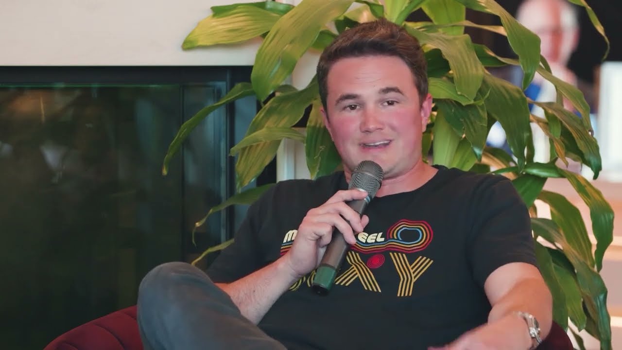 Dallas Hogensen speaking into a microphone while seated at JumpStart’s Founders Unfiltered conversation