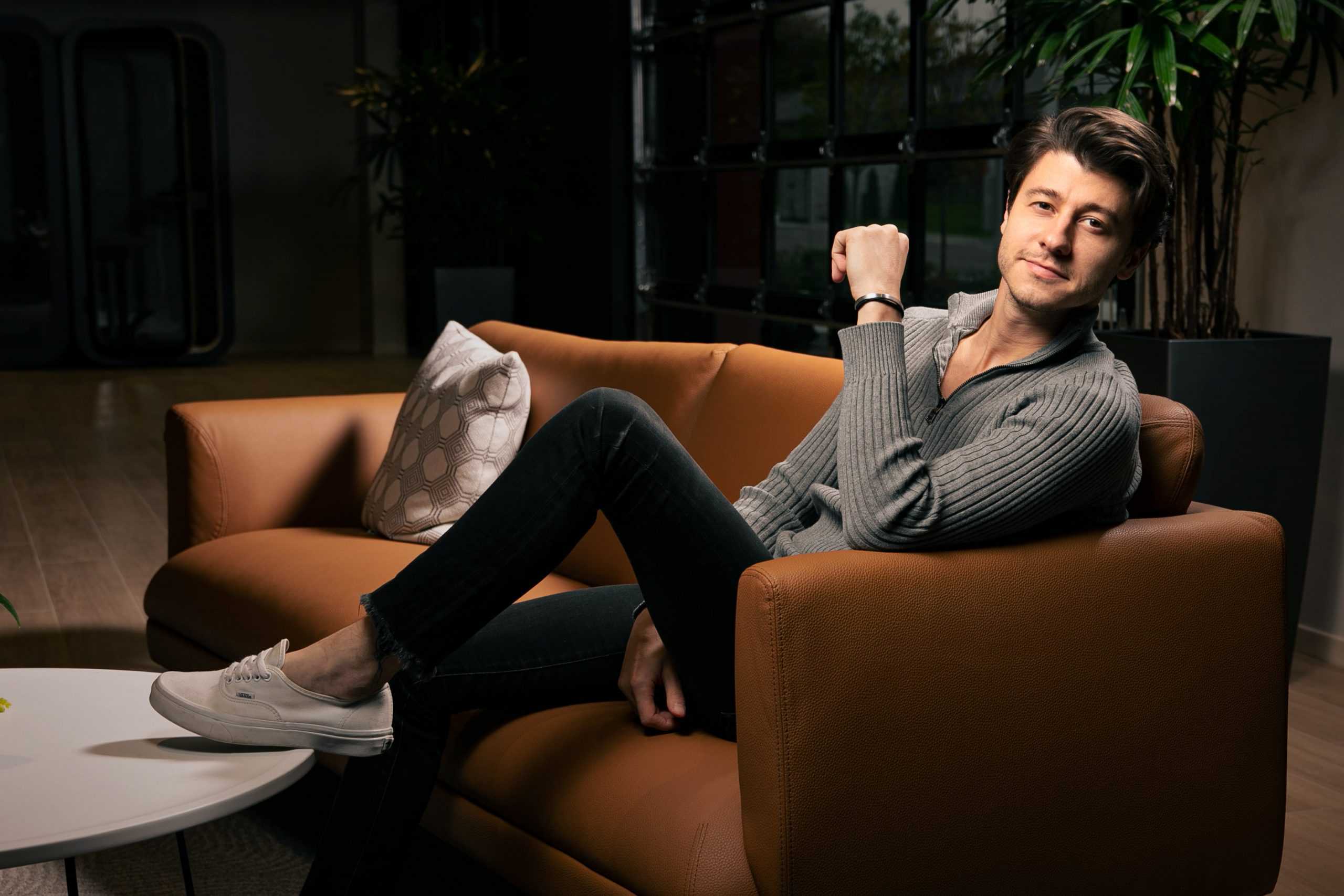 Dalton Luka seated on a brown leather sofa in a modern interior