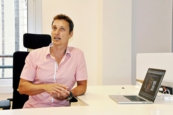 Damir Davidovic seated at a desk beside an open laptop during a 2013 interview