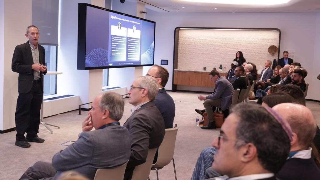 Dan Avida standing beside a presentation screen while an audience listens