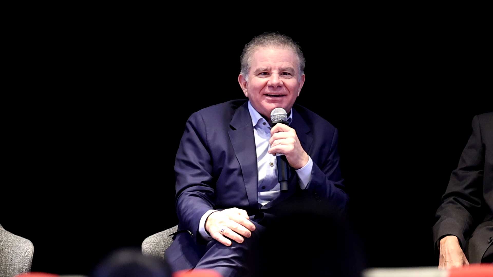 Dan Lejerskar seated on a panel, speaking into a handheld microphone