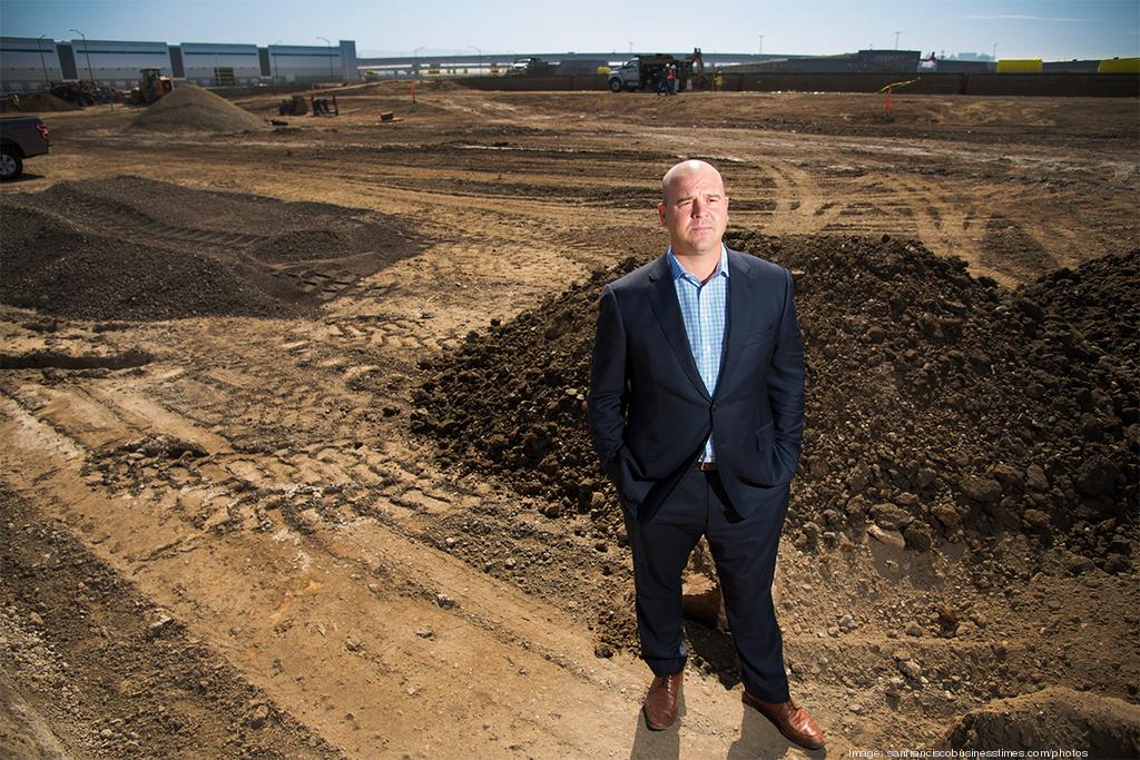 Dan Letter standing on the dirt of an industrial construction site, with earthmoving equipment behind him