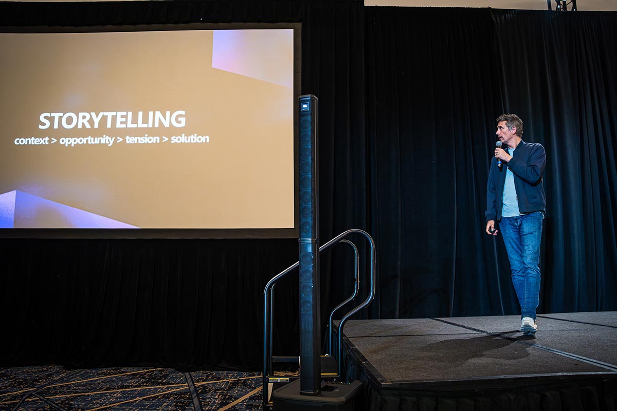 Dan Lewis on stage beside a slide about storytelling at the Seattle AI Startup Summit