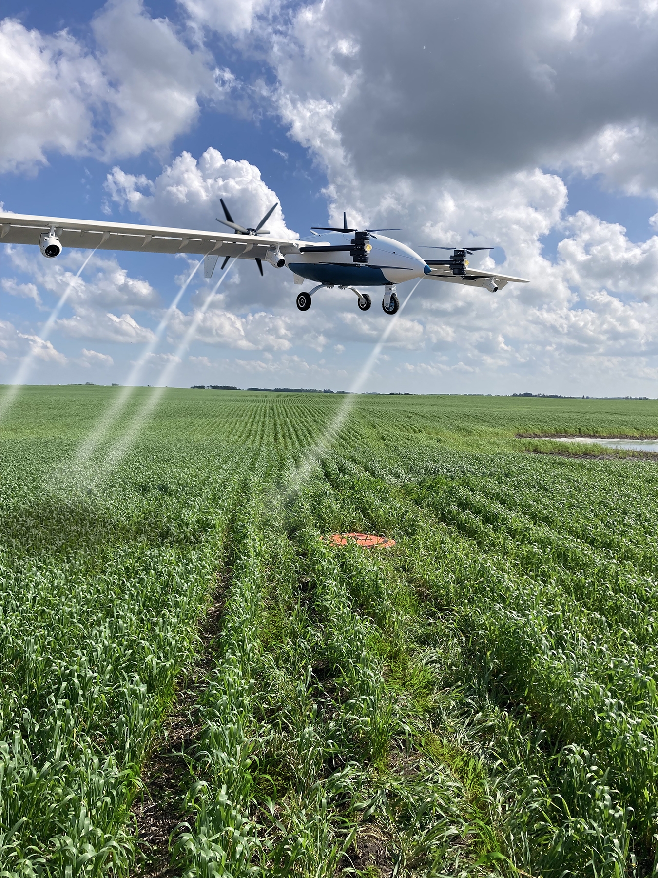 A Precision AI drone flying above a field while spraying