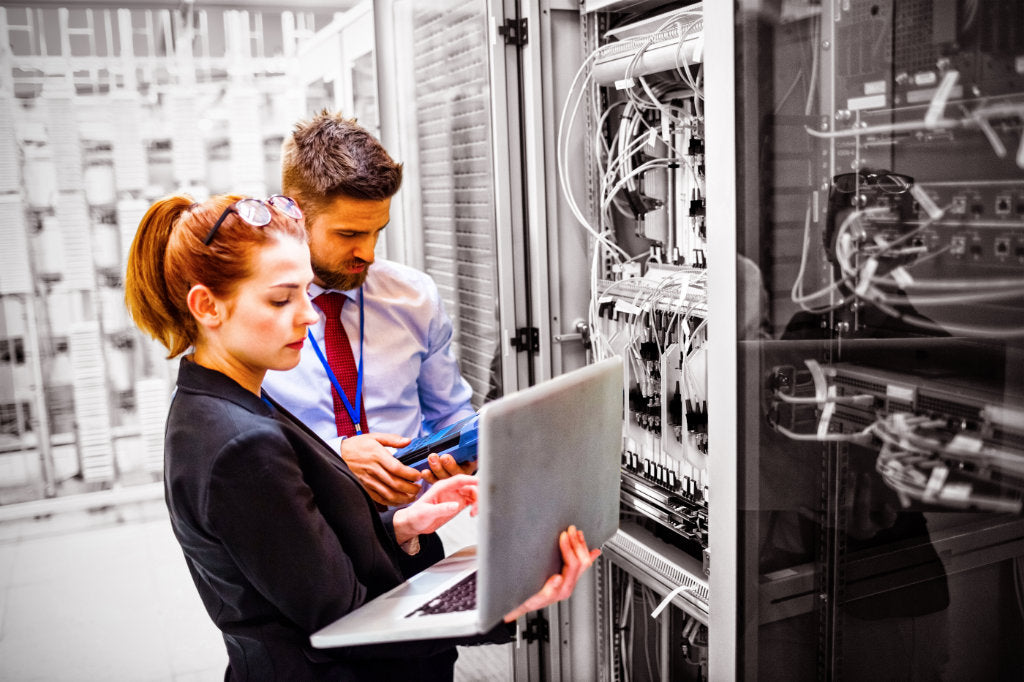 Illustrative networking photograph showing two people working beside equipment racks